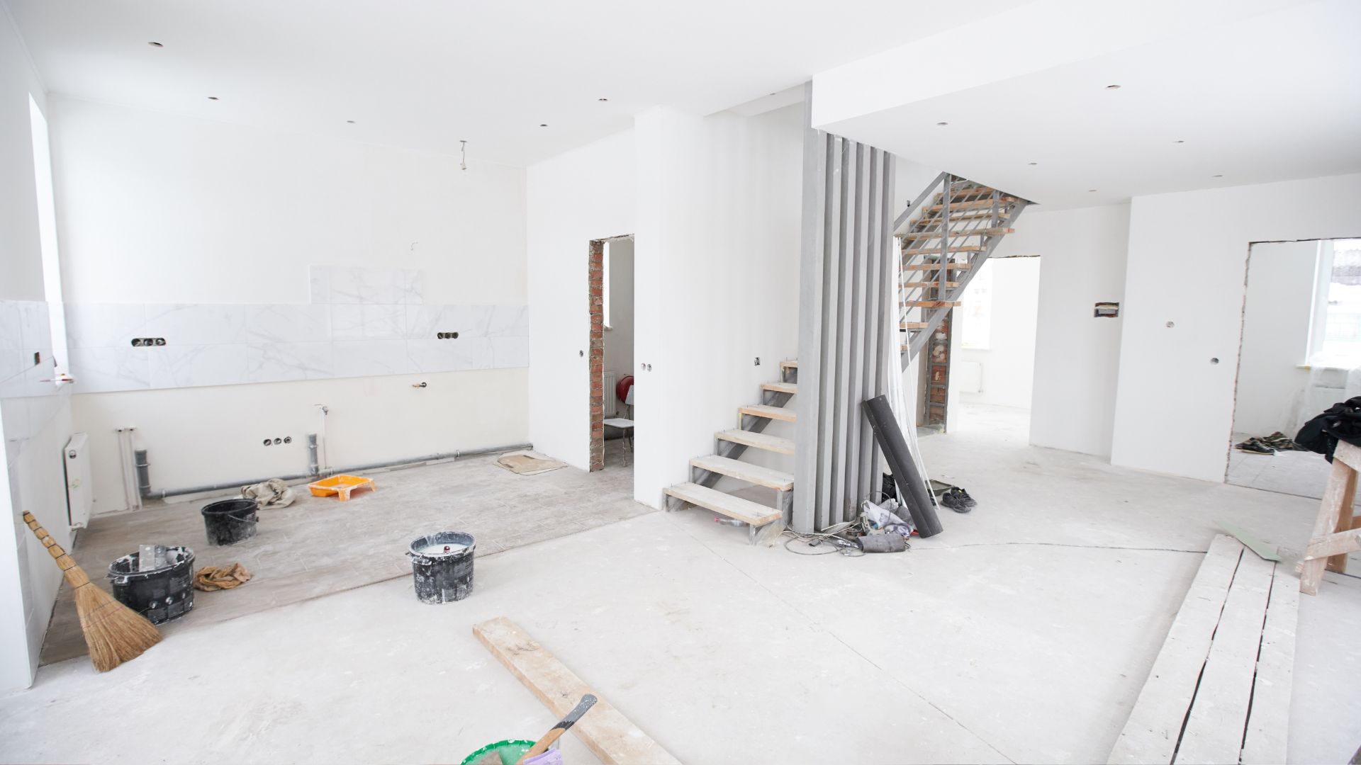 A white room with a staircase and construction tools