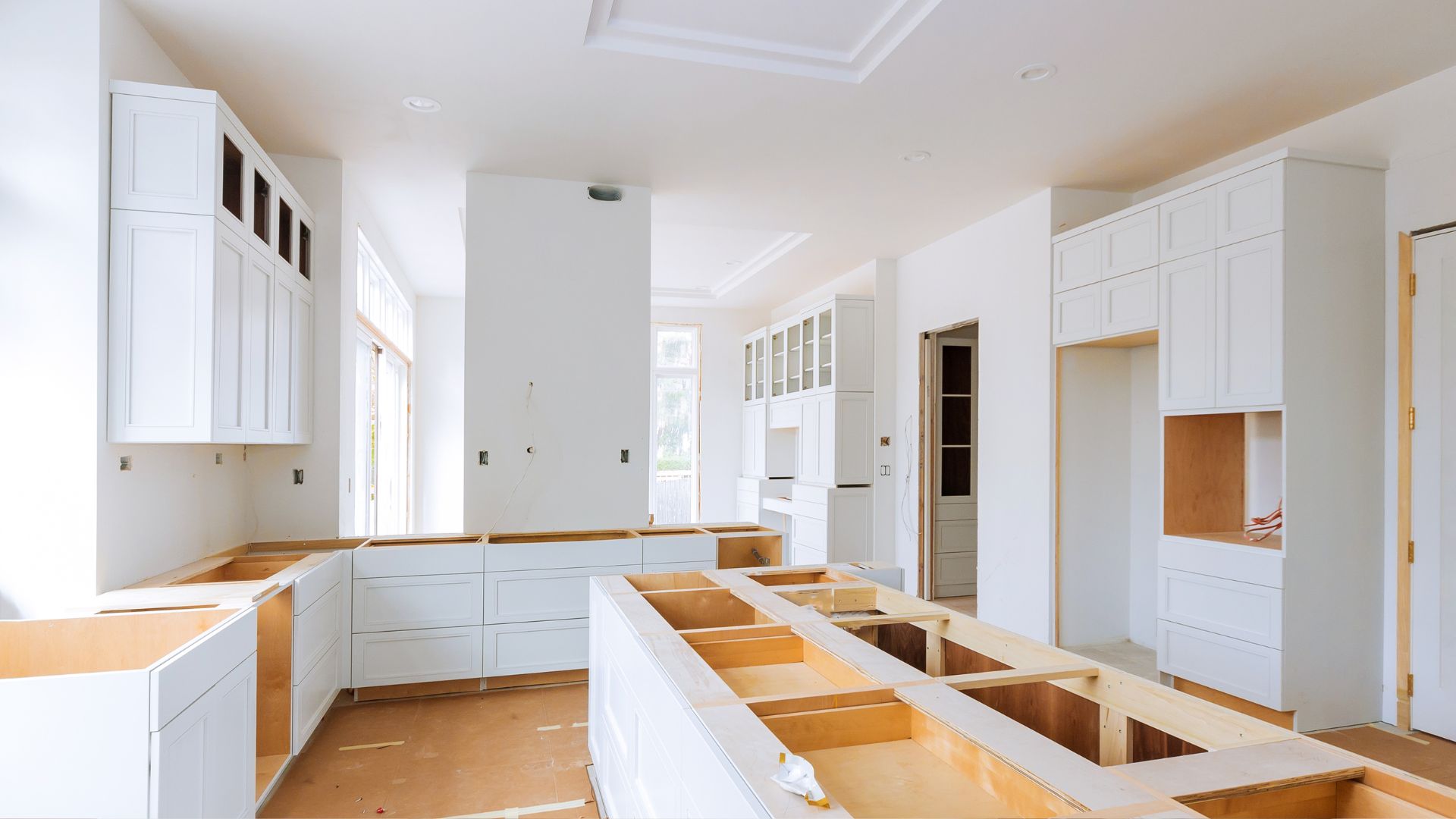 A kitchen being built with white cabinets and drawers