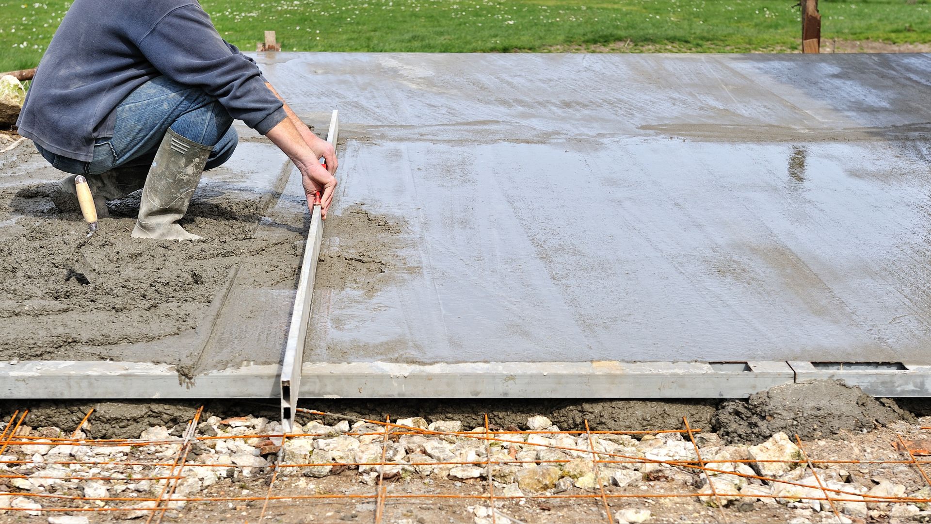 A man is laying concrete on the ground